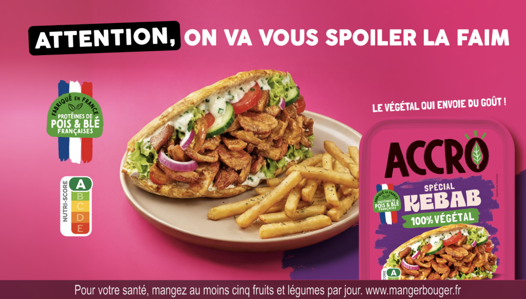 Un sandwich kebab dans un pain pita accompagné de frites dans une assiette, à côté d'un emballage de viande de kebab 100 % végétale Accro faisant la promotion de la nouvelle campagne télévisée en français.